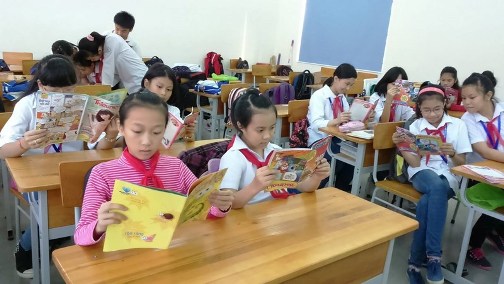 Các em học sinh đọc báo ngoài giờ lên lớp