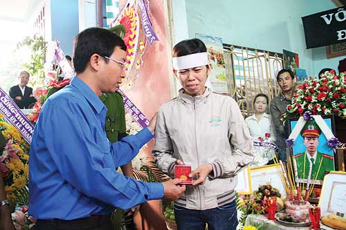 Anh Đặng Quốc Toàn trao Huy hiệu Tuổi trẻ dũng cảm cho gia đình trung úy Lê Thanh Tâm - ảnh: Kim Cương 