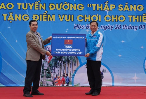 Anh Nguyễn Phi Long, Bí thư BCH Trung ương Đoàn, Chủ tịch Trung ương Hội LHTN Việt Nam (phải) nhận biển tượng trưng trao tặng 100 km đoạn đường Thắp sáng đường quê từ Quỹ Thiện Tâm.