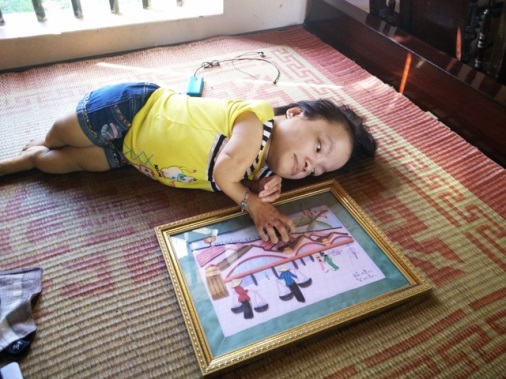 "Cô gái da cam" Cao Thị Út bên bức tranh giấy do chính tay mình tự làm.