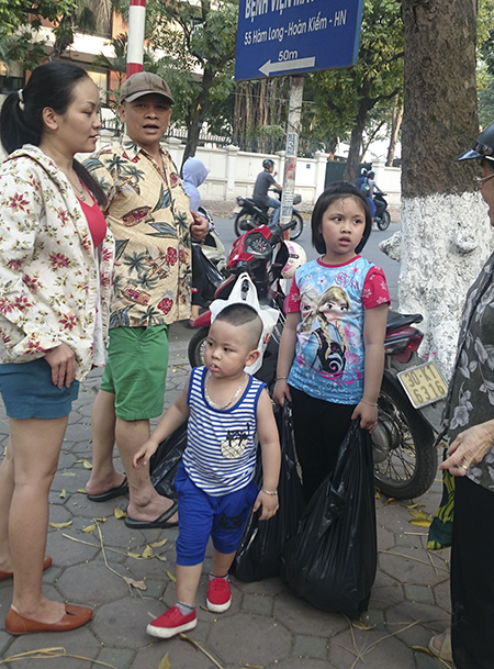 Vợ chồng anh chị Đặng Thị Hồng Thương cùng 2 con nhỏ chờ đợi gần 2 tiếng đồng hồ để mua dưa ủng hộ người dân Quảng Nam