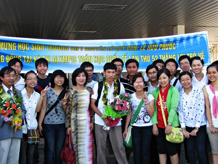  Học sinh Lê Hữu Phước (áo trắng, chính giữa) cùng thầy cô, bạn bè trong ngày trở về TP. cùng tấm HCĐ Olympic Toán quốc tế.