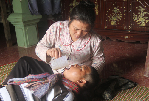 Bà Ninh đang chăm người con trai đầu bị bệnh bại não. Ảnh: Phan Ngọc.