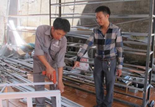  Anh Dương Đình Hưng (bên phải) giúp công nhân của mình trong quá trình làm việc